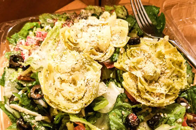 Salad topped with artichoke hearts and grated cheese.