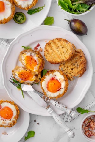 Soft-boiled eggs with toast and greens on a plate.